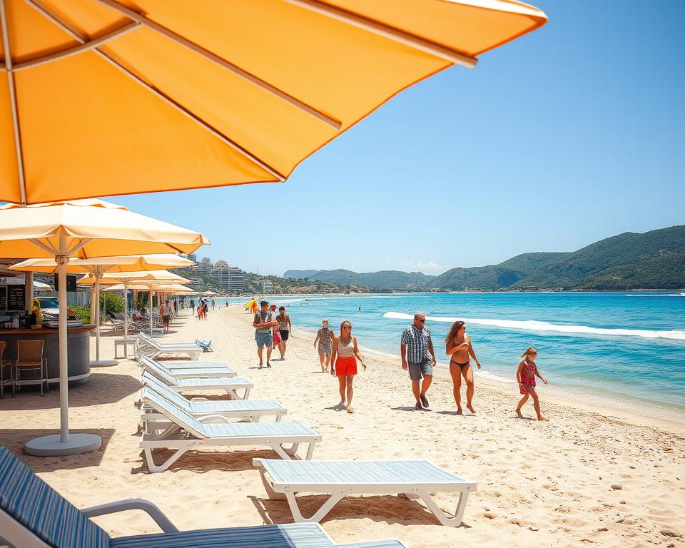A vibrant scene showcasing the infrastructures and amenities on Albanian beaches, with a clear focus on the foreground featuring well-maintained beach facilities like sun loungers, umbrellas, and a beach bar serving refreshments. In the middle ground, depict families enjoying the sun, as well as couples strolling along the sandy shores, all dressed in casual summer attire. The background should feature a stunning coastline with crystal-clear blue waters and lush green hills, under a bright, sunny sky. Use warm lighting to evoke a cheerful, inviting atmosphere and capture the essence of a summer day at the beach, utilizing a wide-angle lens to create depth and detail.